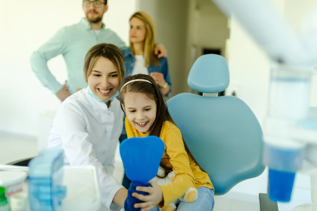 a smiling young girl looking at her smile and teeth after getting her braces off at shining smiles orthodontics in irvine ca